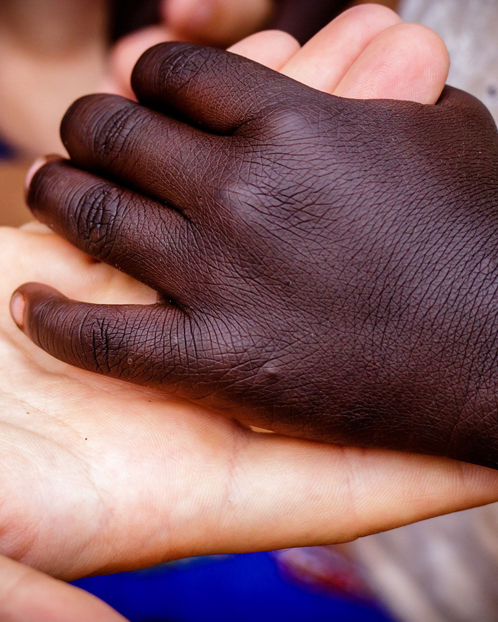 White adult hand holding black children's hand